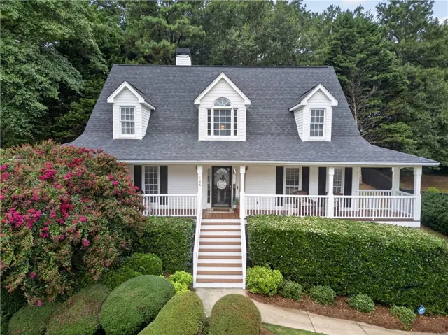Charming residence featuring a classic Gambrel roofline, white siding, and dark shutters