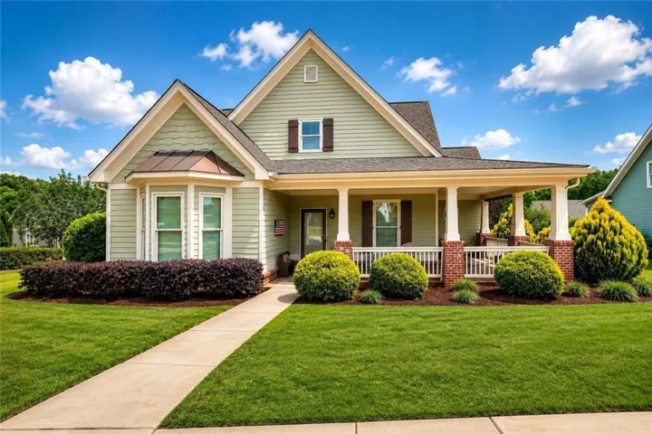 Craftsman-style home featuring light green siding and a covered front porch