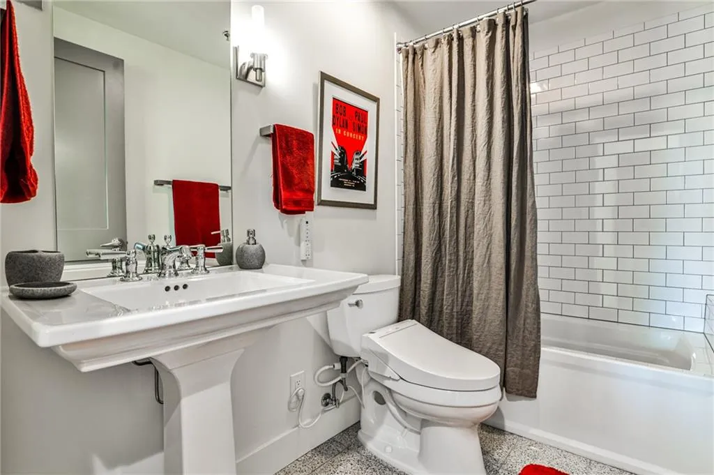 Charming secondary bathroom featuring a pedestal sink, subway tile tub surround, and modern chrome fixtures