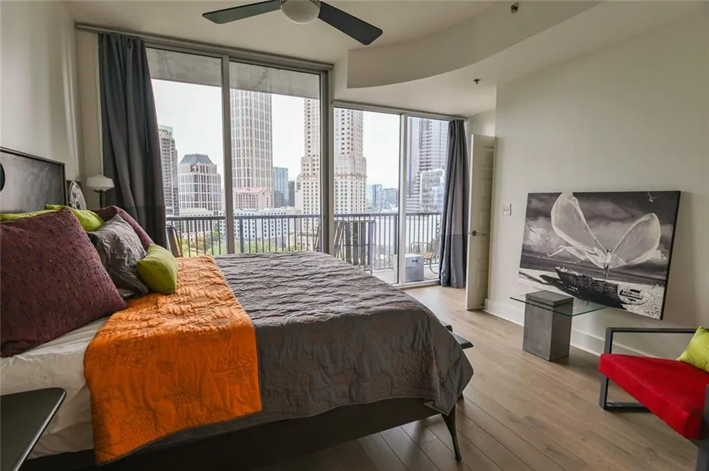 Bedroom with expansive windows, access to outside, wood finished floors, and a ceiling fan