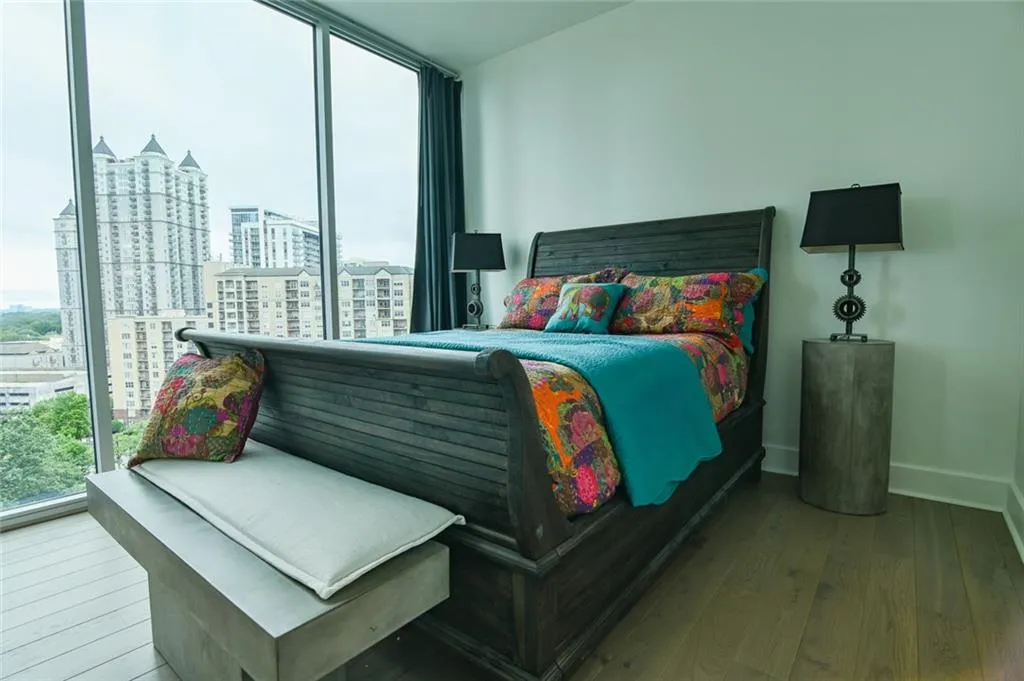 Bedroom featuring hardwood / wood-style floors, a view of city, and a wall of windows