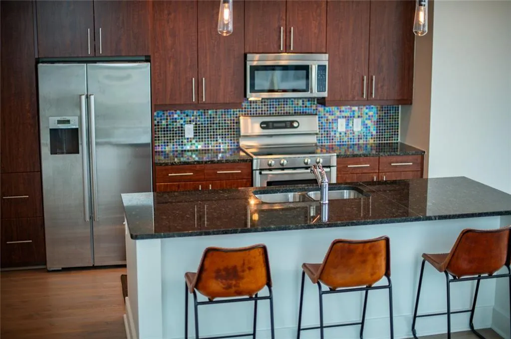 Kitchen featuring appliances with stainless steel finishes, decorative backsplash, a breakfast bar area, and an island with sink