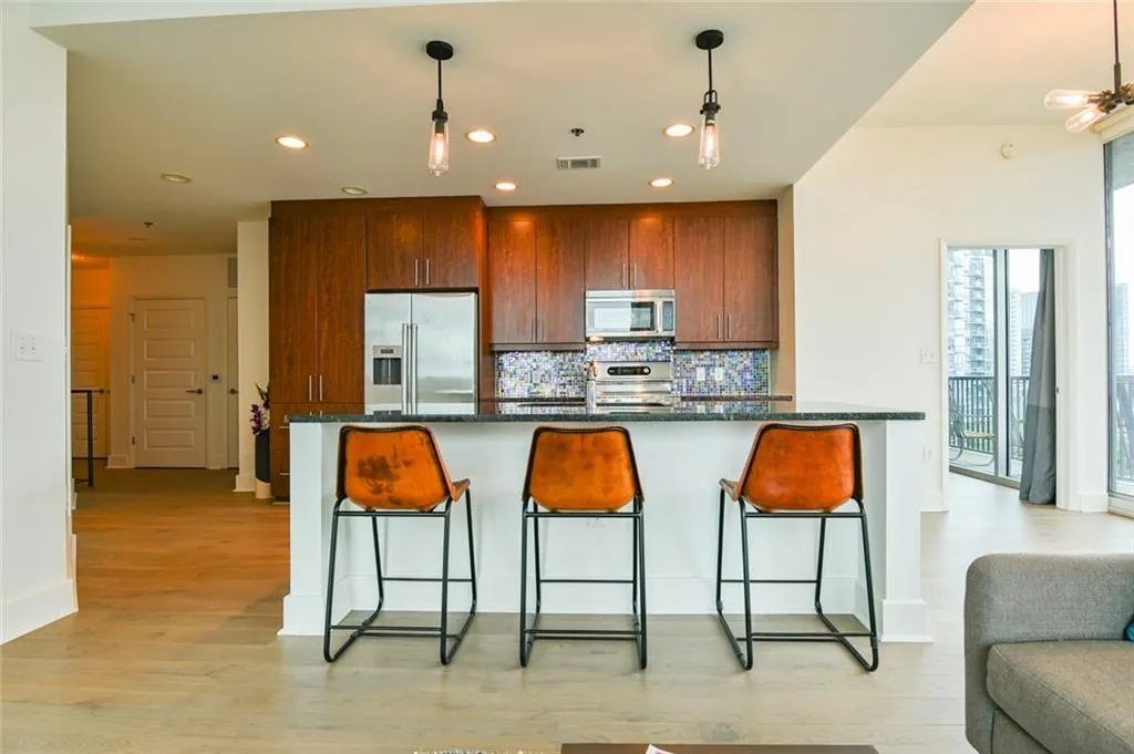 Kitchen with stainless steel appliances, decorative backsplash, recessed lighting, light wood finished floors, and decorative light fixtures