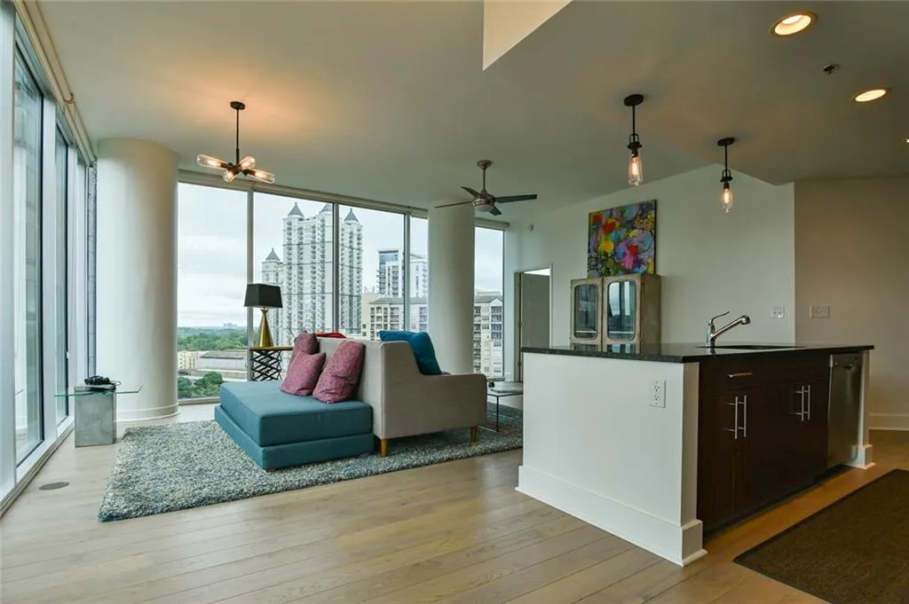 Kitchen with dark countertops, light wood-style floors, open floor plan, floor to ceiling windows, and an island with sink