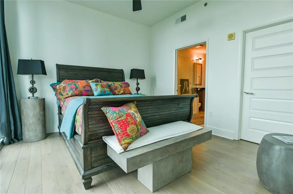 Bedroom with wood finished floors, ensuite bath, and a ceiling fan