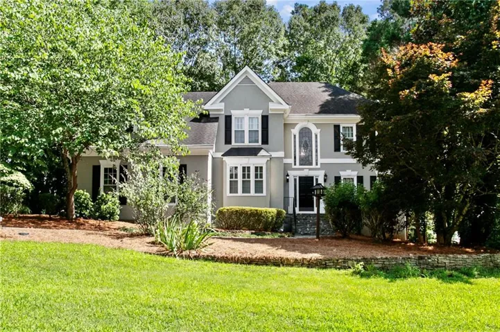 Two-story residence featuring a gray exterior, black shutters, and an arched entry window