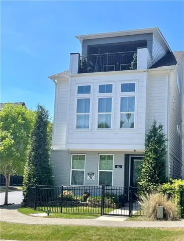 Modern three-story residence featuring a clean white exterior with horizontal siding, expansive multi-pane windows across the second level, and a rooftop deck with black metal railings