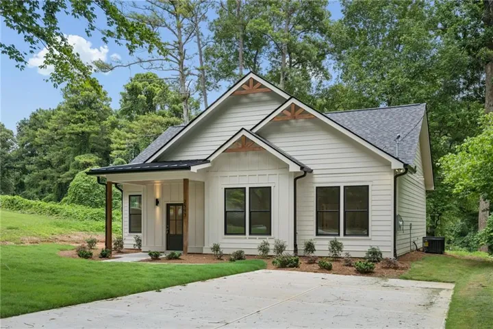 Modern farmhouse-style exterior featuring white horizontal siding, black-framed windows, and a black front door with glass panels