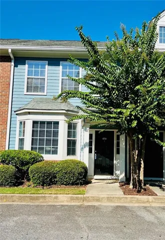 Blue horizontal siding with white trim, bay window, dark entry door, and established front landscaping