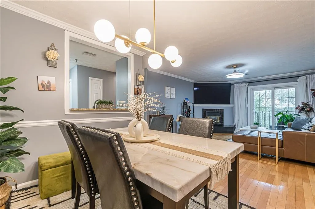Dining space with ornamental molding, a tiled fireplace, and wood-type flooring