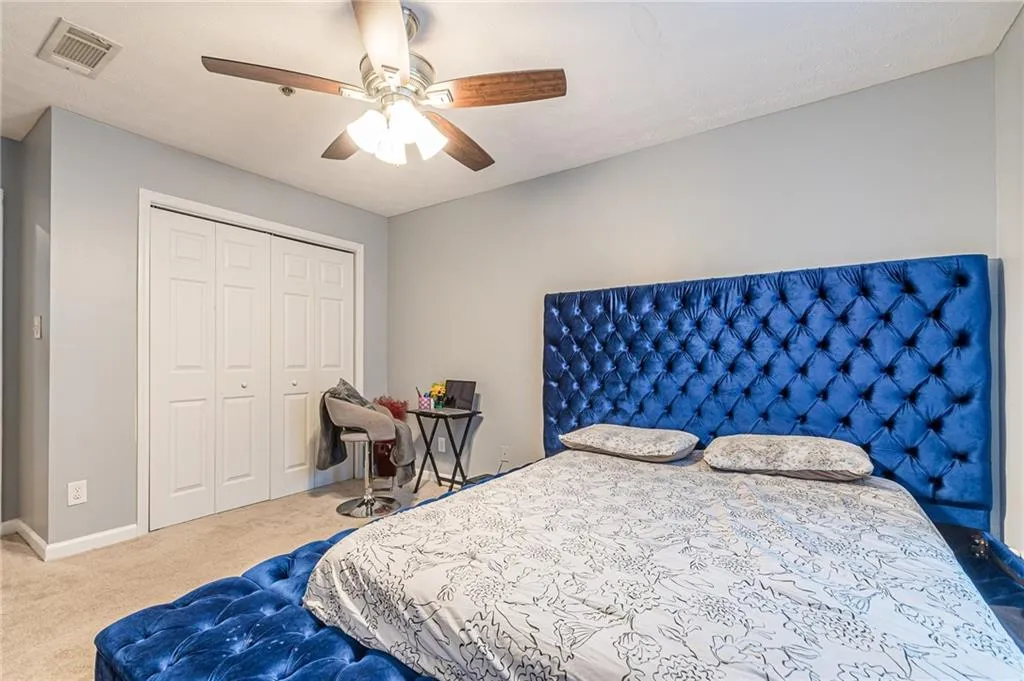 Carpeted bedroom with a closet and ceiling fan