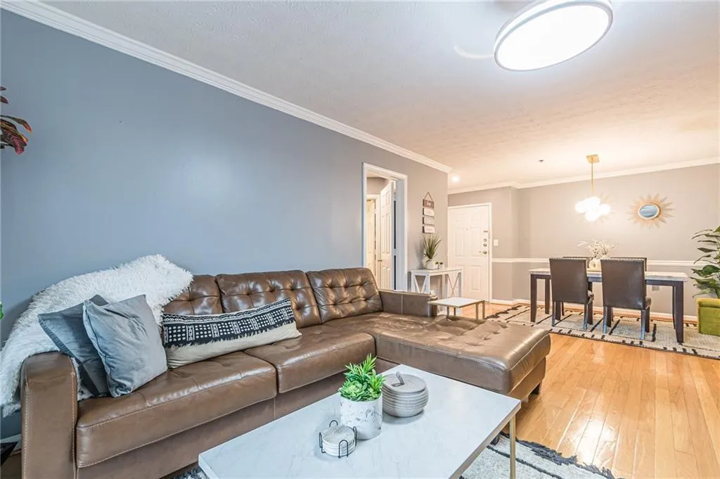 Living area featuring ornamental molding, wood-type flooring, a chandelier, and a textured ceiling