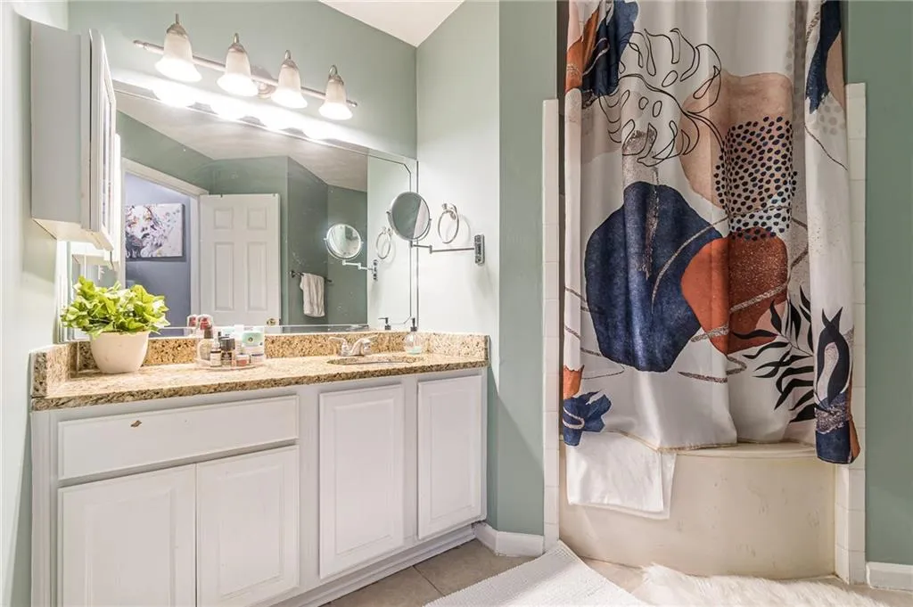 Full bath featuring vanity, light tile patterned flooring, and a shower with shower curtain