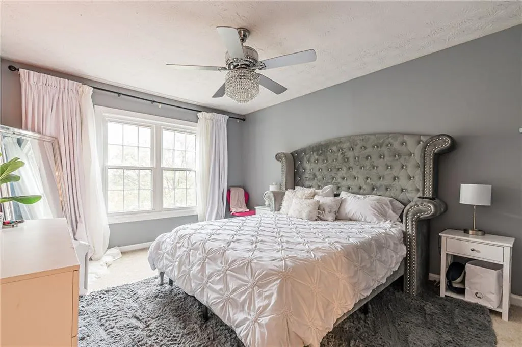 Carpeted bedroom featuring a textured ceiling and ceiling fan