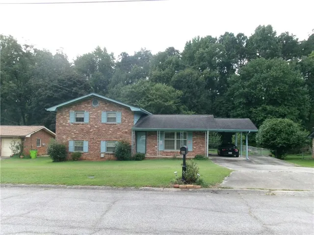 Brick exterior with light blue shutters, attached carport, and a detached garage