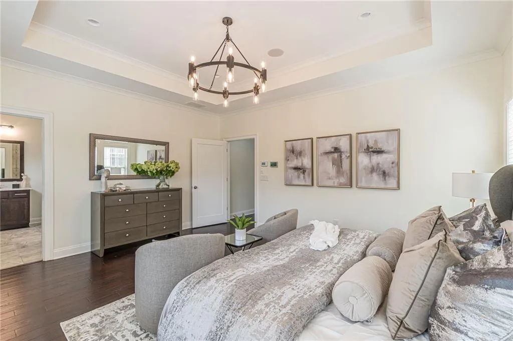 Bedroom featuring crown molding, a raised ceiling, dark hardwood / wood-style flooring, and a chandelier