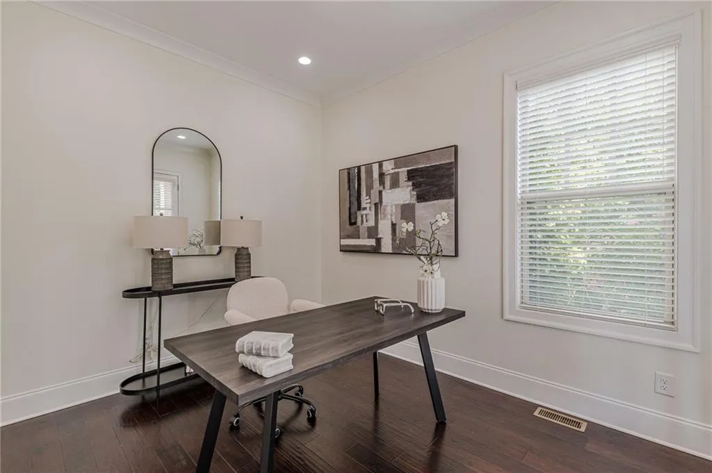 Office space featuring a healthy amount of sunlight, wood-type flooring, and ornamental molding