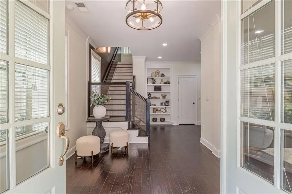 Foyer featuring an inviting chandelier, crown molding, and dark hardwood / wood-style flooring