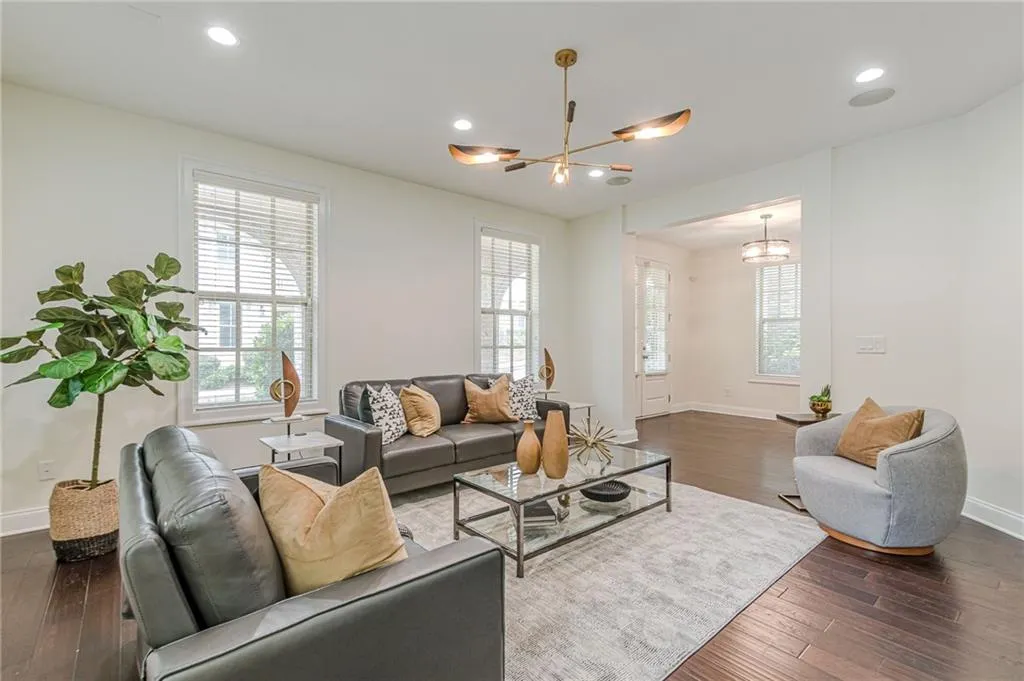 Living room with an inviting chandelier, plenty of natural light, and dark hardwood / wood-style floors