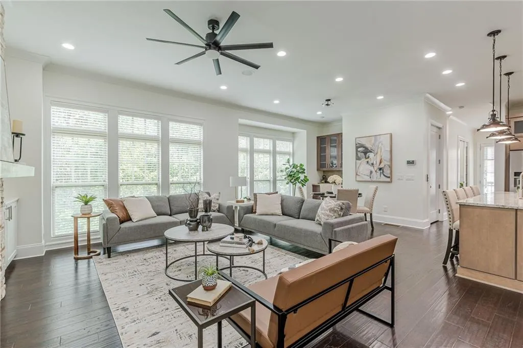 Living room featuring dark wood-type flooring, ornamental molding, and ceiling fan