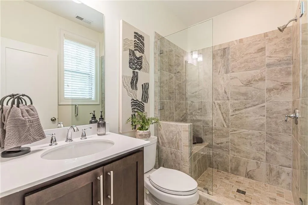 Bathroom featuring toilet, vanity, and a tile shower