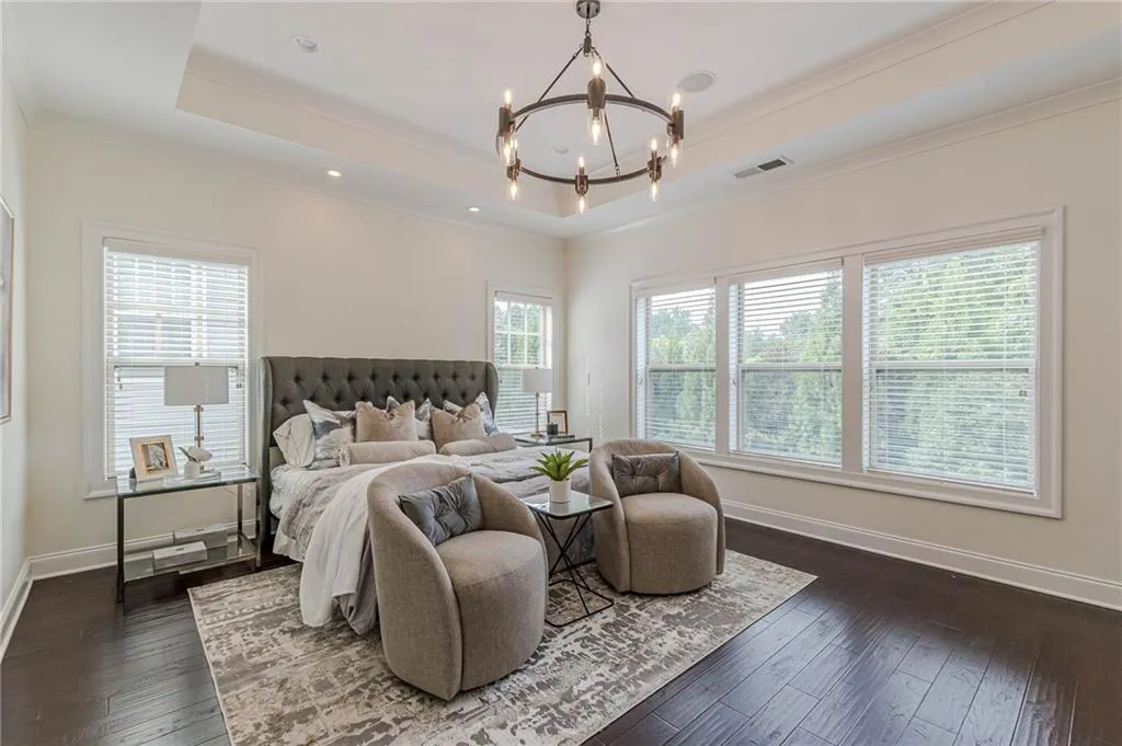 Bedroom with an inviting chandelier, dark hardwood / wood-style floors, ornamental molding, and a tray ceiling