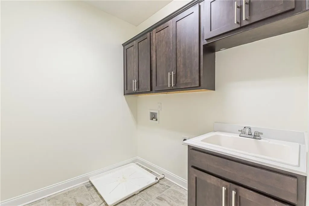 Laundry area with sink, cabinets, hookup for a washing machine, and light tile patterned floors