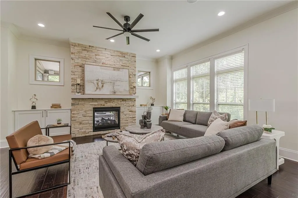 Living room with a fireplace, dark hardwood / wood-style floors, ceiling fan, and ornamental molding