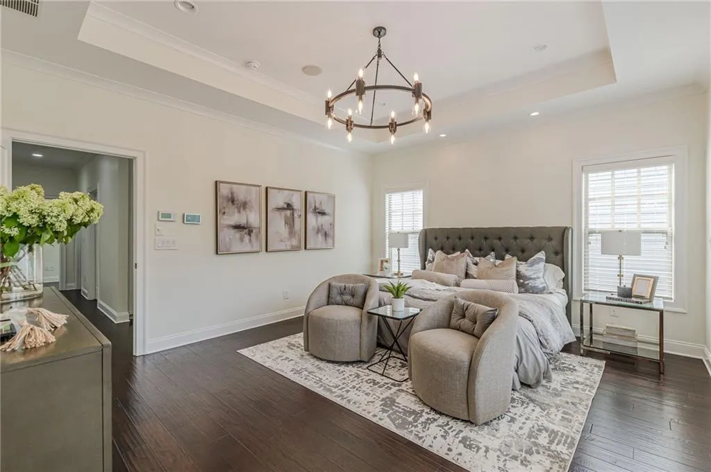 Bedroom with an inviting chandelier, dark wood-type flooring, a tray ceiling, and multiple windows