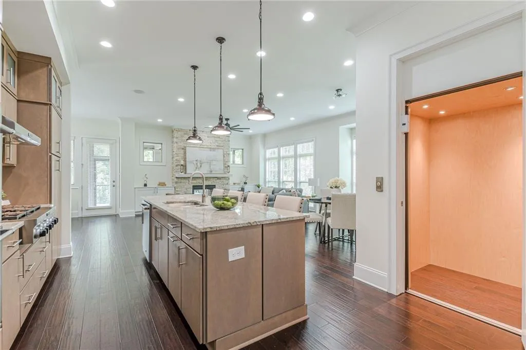 Kitchen featuring sink, dark hardwood / wood-style floors, light stone counters, and a large island