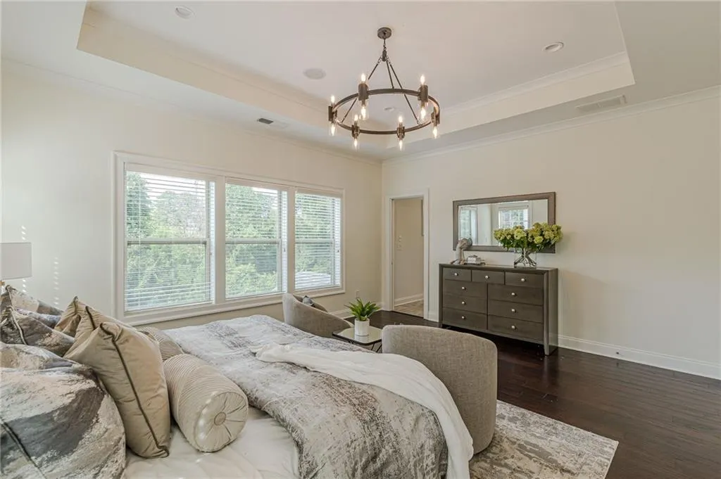 Bedroom featuring an inviting chandelier, dark hardwood / wood-style floors, a raised ceiling, and ornamental molding