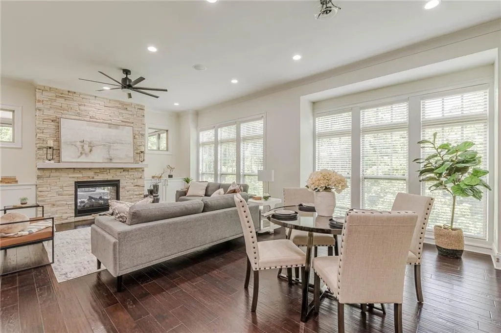 Living room with ceiling fan, a stone fireplace, dark hardwood / wood-style flooring, and plenty of natural light