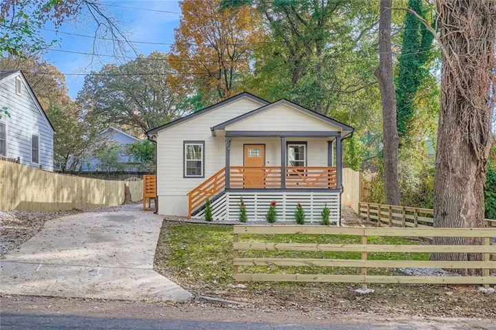 Contemporary bungalow featuring a covered front porch with natural wood railings, white siding, and dark trim
