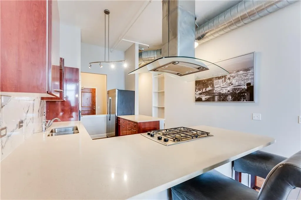Kitchen featuring light countertops, a kitchen bar, island exhaust hood, stainless steel appliances, and a sink