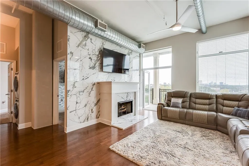 Living area featuring dark wood finished floors, a fireplace, stacked washer and clothes dryer, and baseboards