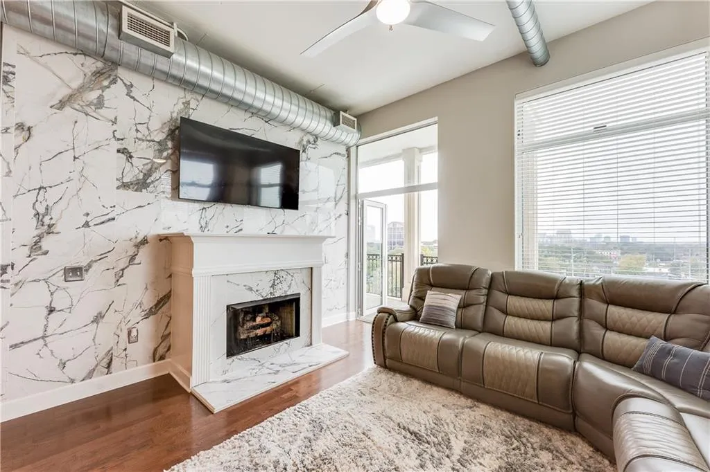 Living room with wood finished floors, baseboards, visible vents, a fireplace, and ceiling fan