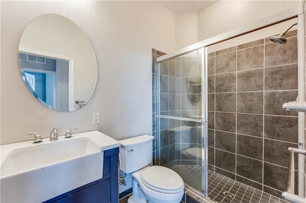 Bathroom with vanity, toilet, and a stall shower