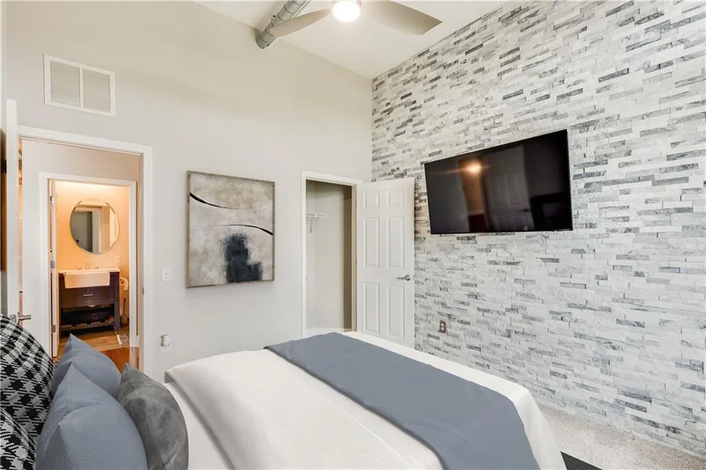 Bedroom featuring visible vents, an accent wall, a closet, a ceiling fan, and a sink