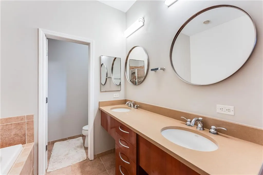 Full bathroom with a sink, a relaxing tiled tub, toilet, and tile patterned floors