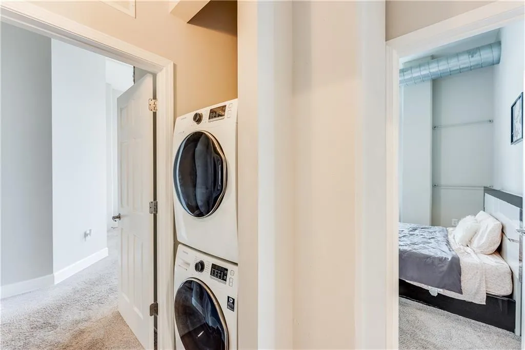 Laundry area featuring laundry area, baseboards, carpet, and stacked washer and dryer