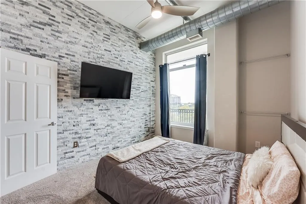 Bedroom with an accent wall, ceiling fan, and carpet floors