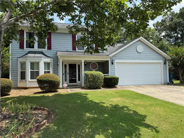 Light blue siding exterior featuring a covered porch entrance and a two-car garage