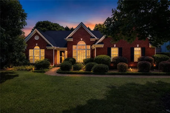 Brick exterior featuring a gabled roofline, arched windows, and a paved walkway