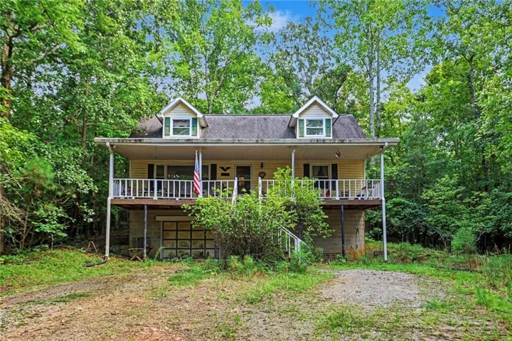 Elevated home with a covered front porch, white railing, and two dormer windows