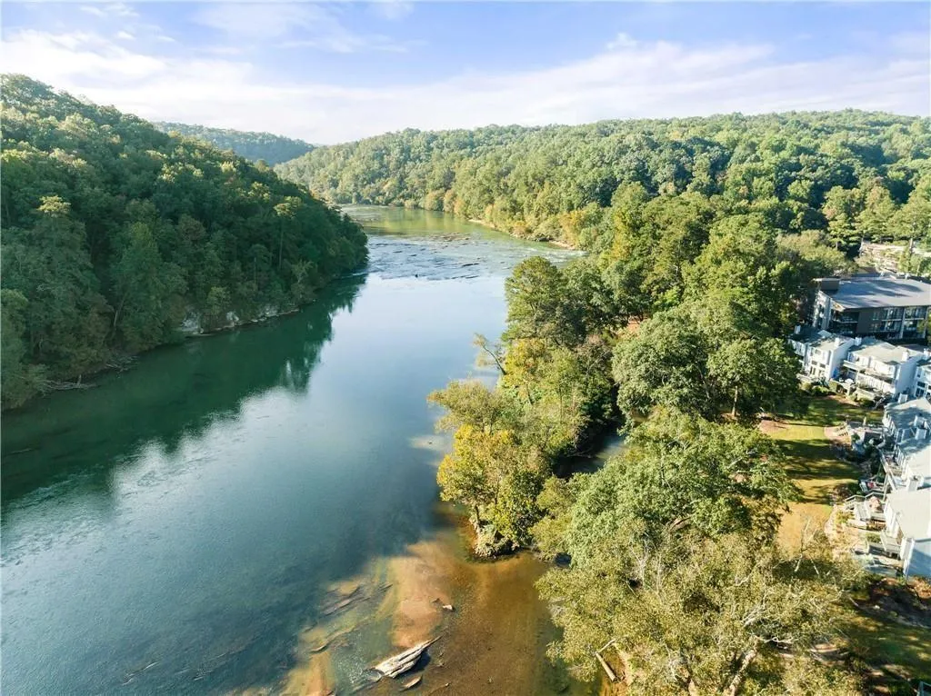 Aerial view of property's location with a heavily wooded area and a large body of water