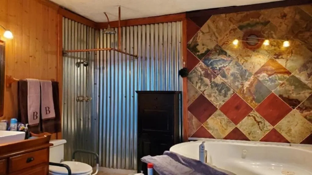 Bathroom featuring vanity, walk in shower, and wood walls
