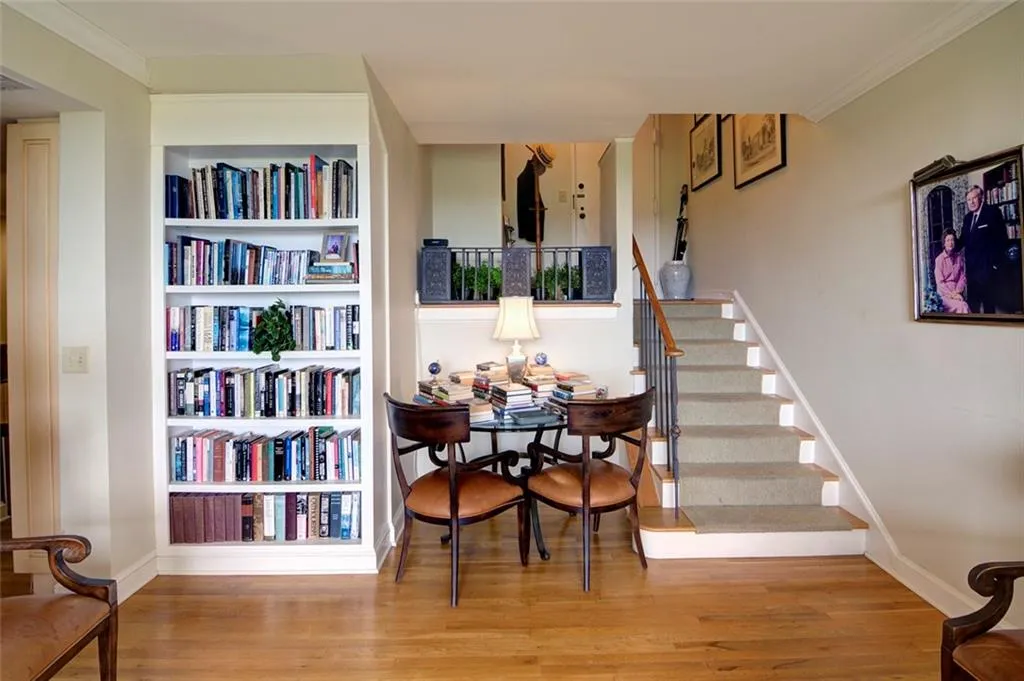 Stairway with wood finished floors, baseboards, crown molding, and built in features