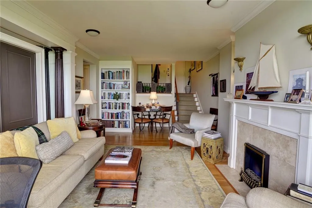 Living area with wood finished floors, crown molding, a fireplace, stairway, and built in features