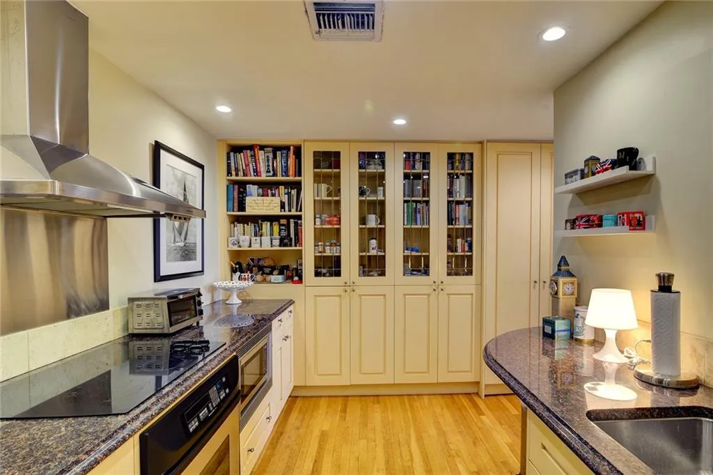 Kitchen with extractor fan, wall oven, light wood-style floors, recessed lighting, and stainless steel microwave