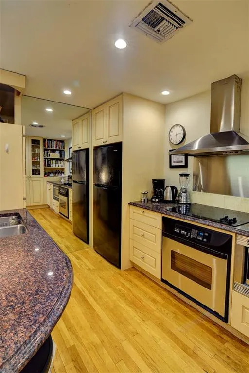 Kitchen KitchenAid vent hood, cream cabinetry, light wood-style floors, and recessed lighting